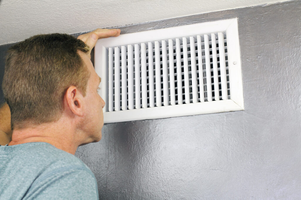 Homeowner looking at vent as AC blows warm air